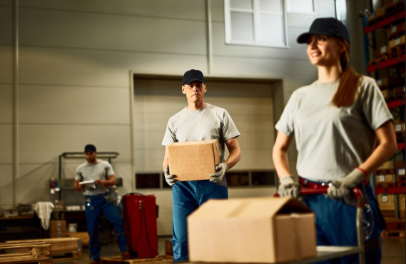 General laborer warehouse workers sorting boxes on conveyor belt inside Amazon-style fulfillment center, USA
