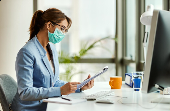 NP checking patient files with a wall calendar showing Monday–Thursday work schedule.